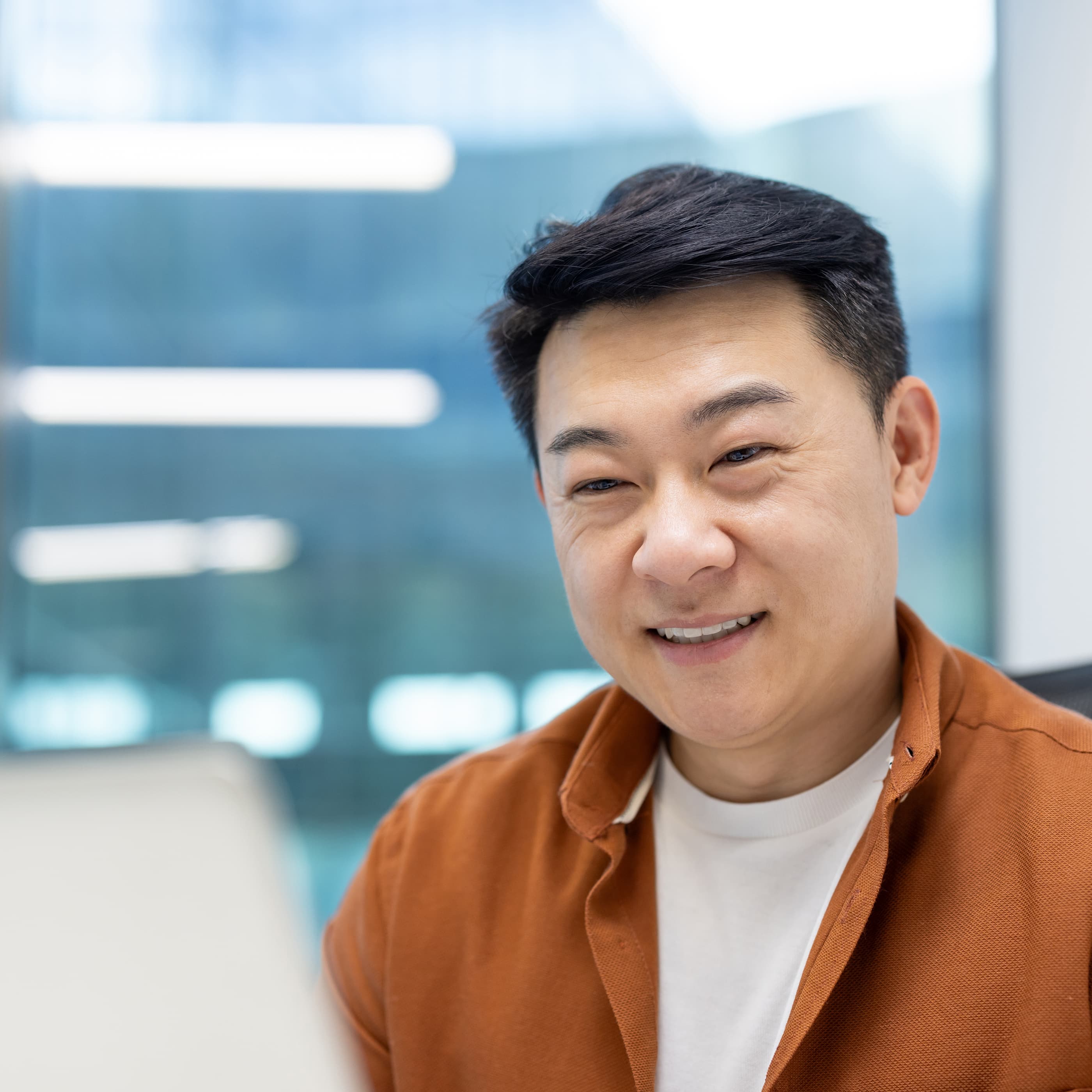 戴眼镜、戴耳机的男子正在电脑前敲击键盘。